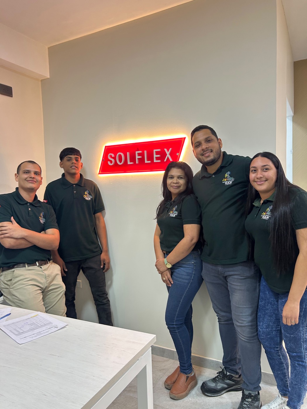 Equipo de Soluciones Corporativas M&M en oficina, junto al letrero Solflex